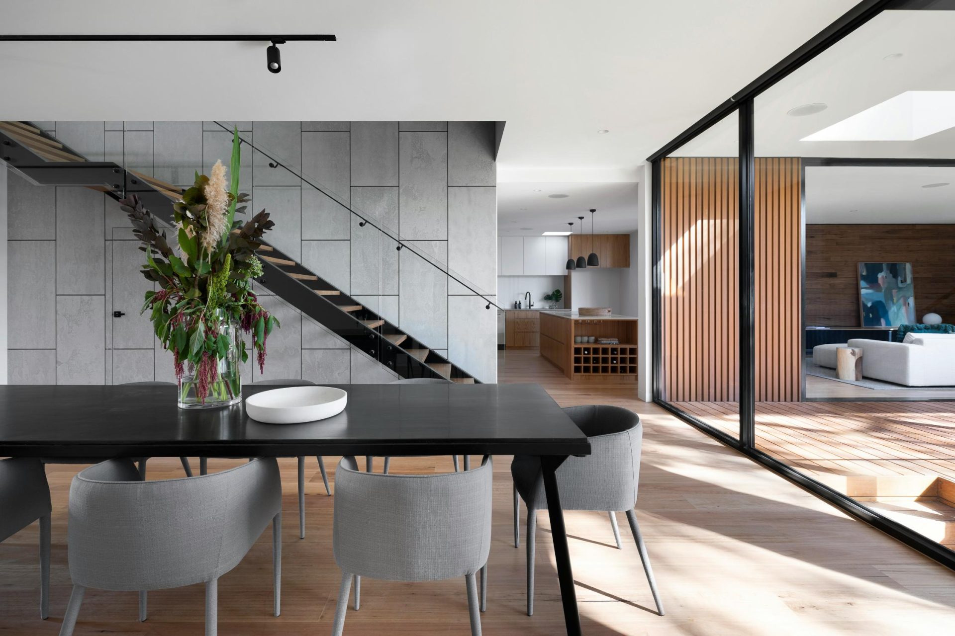 Modern dining area with open stairway and glass walls